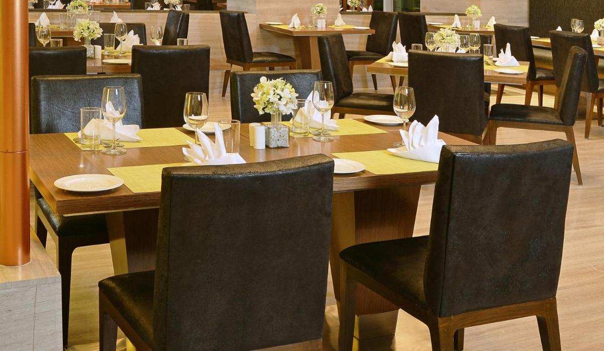 a wooden table with chairs and plates and wine glasses at Welcomhotel by ITC Hotels, Richmond Road, Bengaluru in Bengaluru