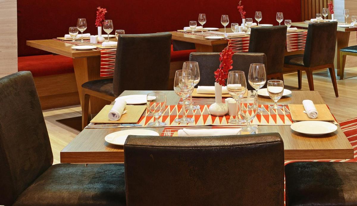 a dining room with tables and chairs with wine glasses at Welcomhotel by ITC Hotels, Richmond Road, Bengaluru in Bengaluru