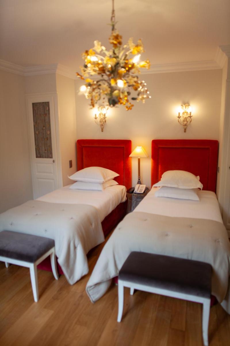 Deux lits dans une chambre avec un lustre dans l'établissement Le Domaine de Beaulieu, à Busnes