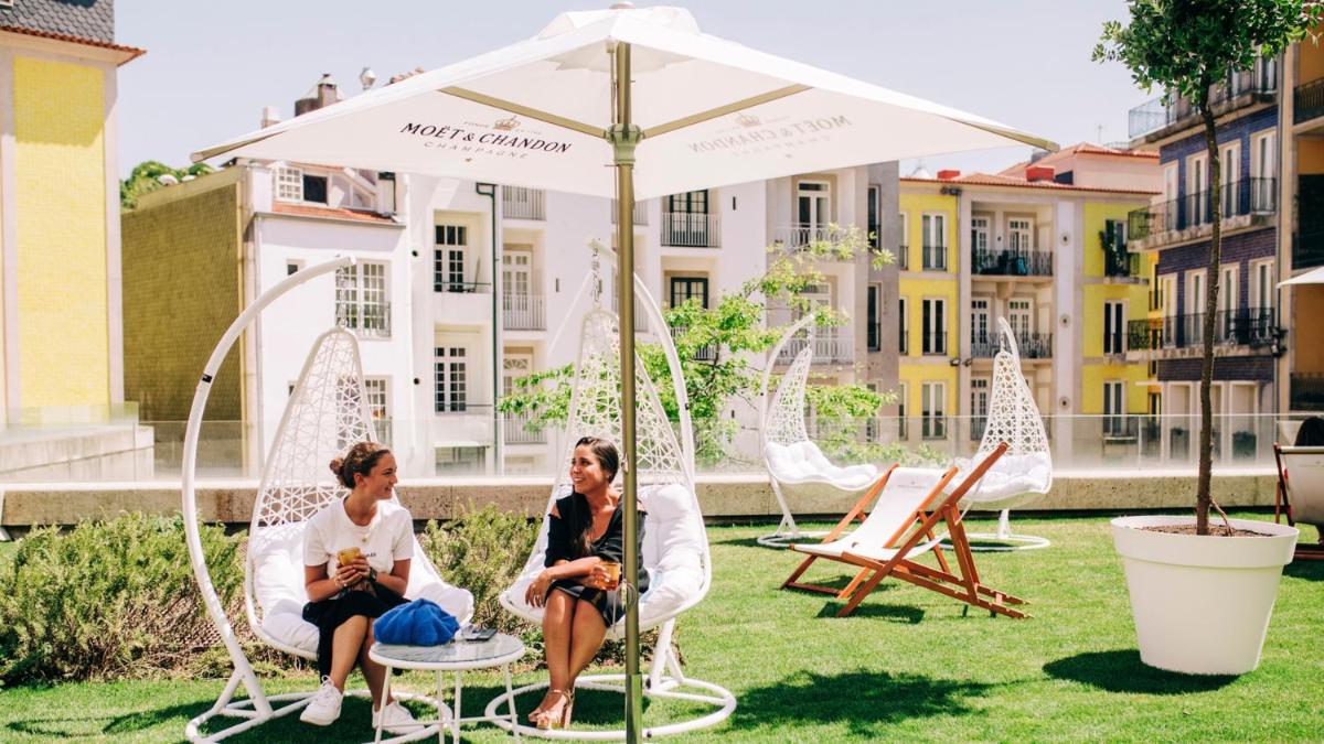 duas mulheres sentadas em cadeiras debaixo de um guarda-chuva em InterContinental Porto - Palacio das Cardosas by IHG no Porto