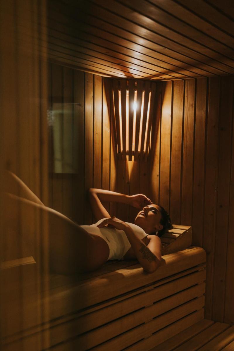 Uma mulher está deitada em uma sauna. em Sweet Atlantic Hotel & Spa na Figueira da Foz