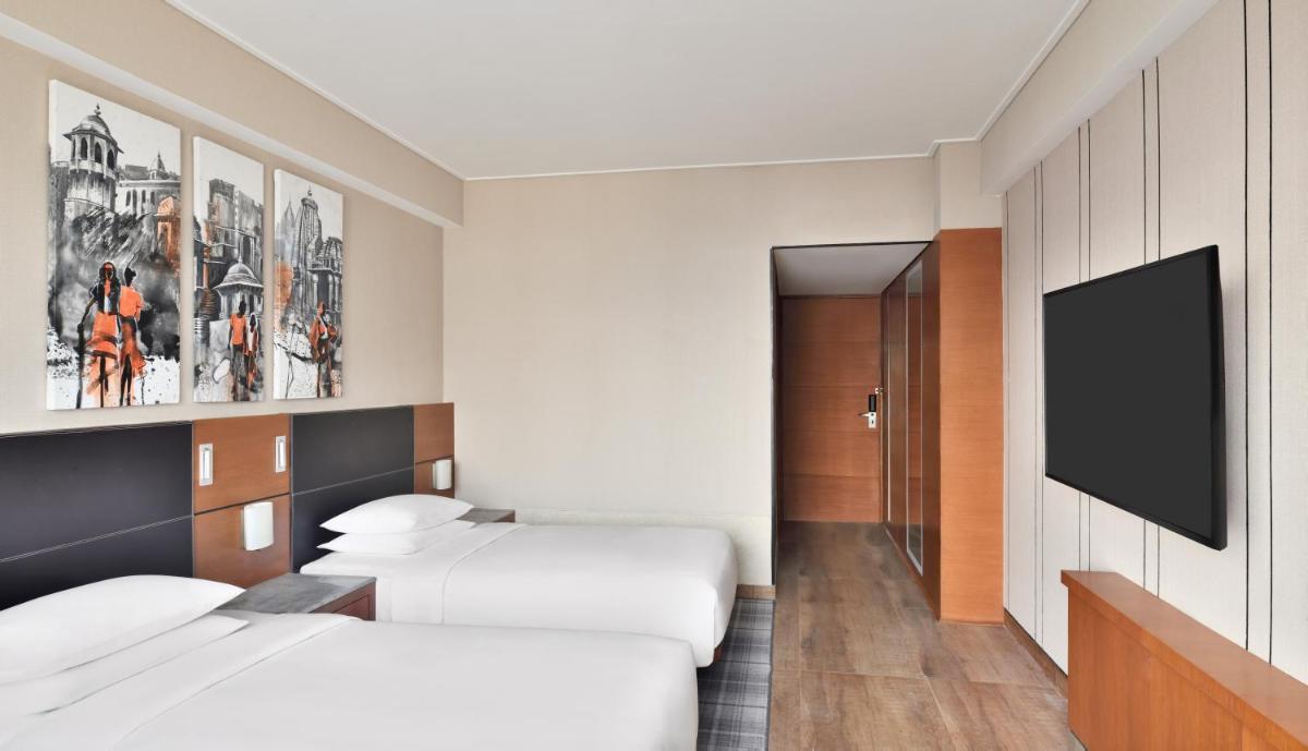 a hotel room with two beds and a flat screen tv at Hyatt Centric Janakpuri New Delhi in New Delhi