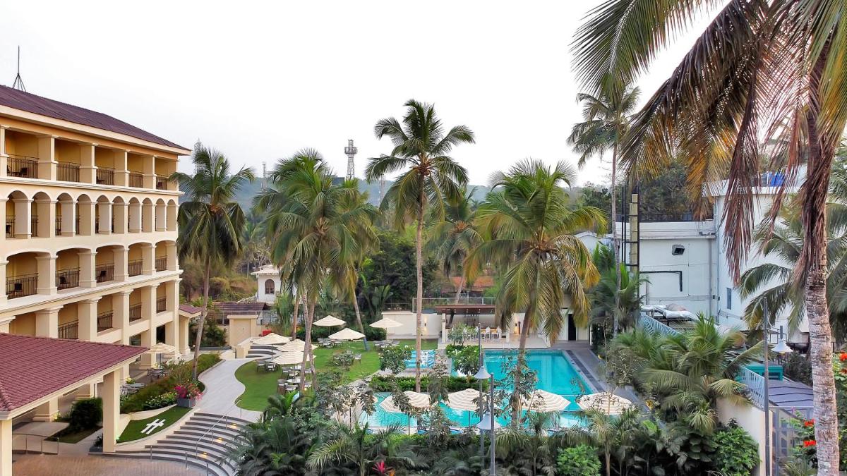 an aerial view of a resort with a pool and palm trees at Holiday Inn Goa Candolim in Candolim an aerial view of a resort with a pool and palm trees at Holiday Inn Goa Candolim in Candolim