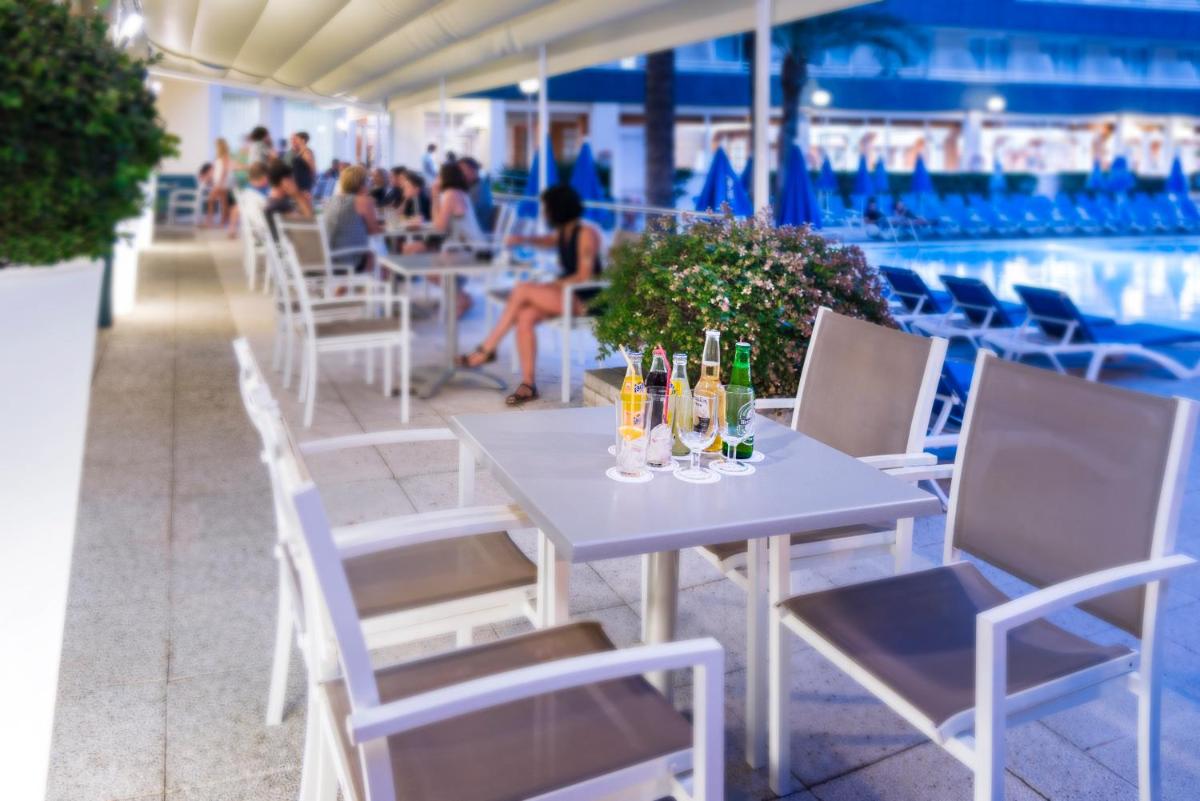 una mesa con botellas y vasos junto a una piscina en GHT Aquarium & Spa, en Lloret de Mar