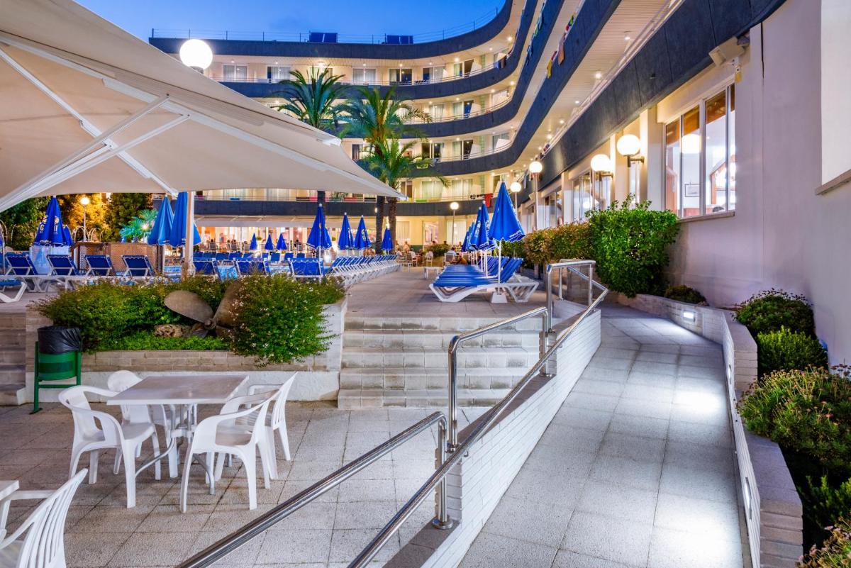 un restaurante con mesas, sillas y sombrillas azules en GHT Aquarium & Spa, en Lloret de Mar