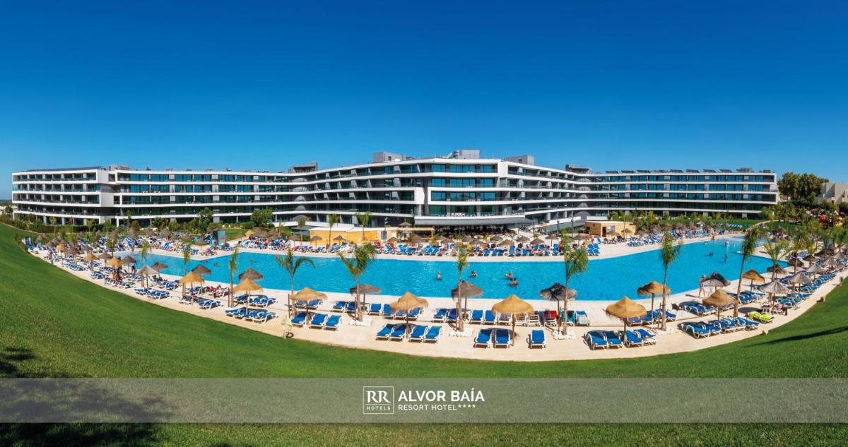um resort com uma grande piscina com cadeiras e pessoas em RR Alvor Baía Resort em Alvor um resort com uma grande piscina com cadeiras e pessoas em RR Alvor Baía Resort em Alvor