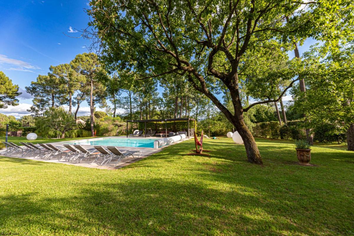 une personne debout à côté d'un arbre à côté d'une piscine dans l'établissement Les Sables d'Ocre & SPA, à Roussillon