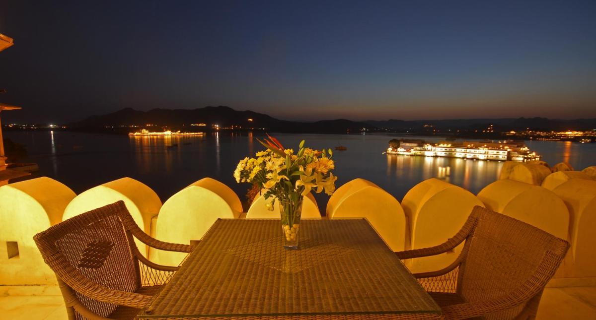 a table with a vase of flowers on it with chairs at Taj Fateh Prakash Palace Udaipur in Udaipur