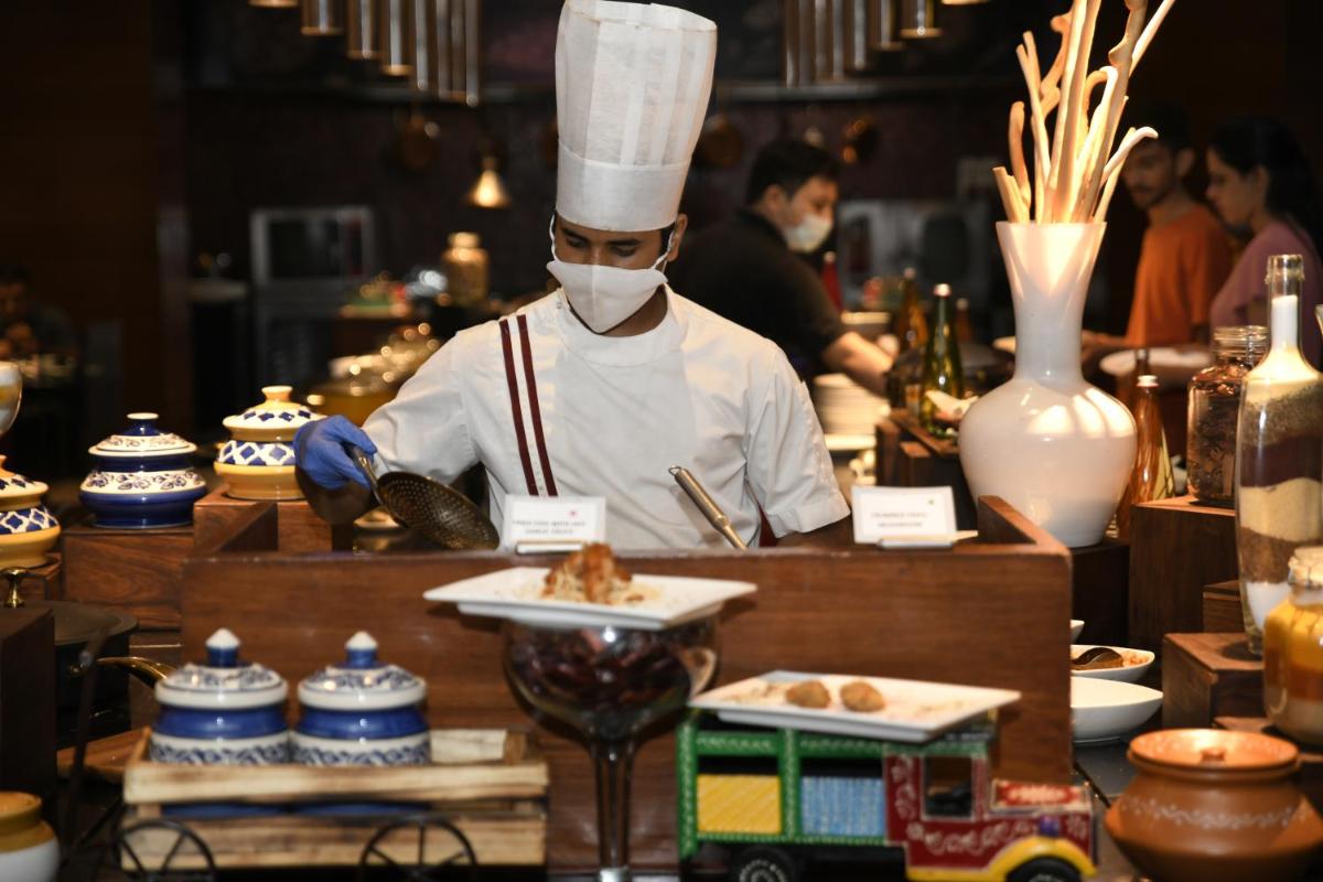 a chef wearing a mask preparing food in a restaurant at Radisson Blu Plaza Delhi Airport in New Delhi a chef wearing a mask preparing food in a restaurant at Radisson Blu Plaza Delhi Airport in New Delhi