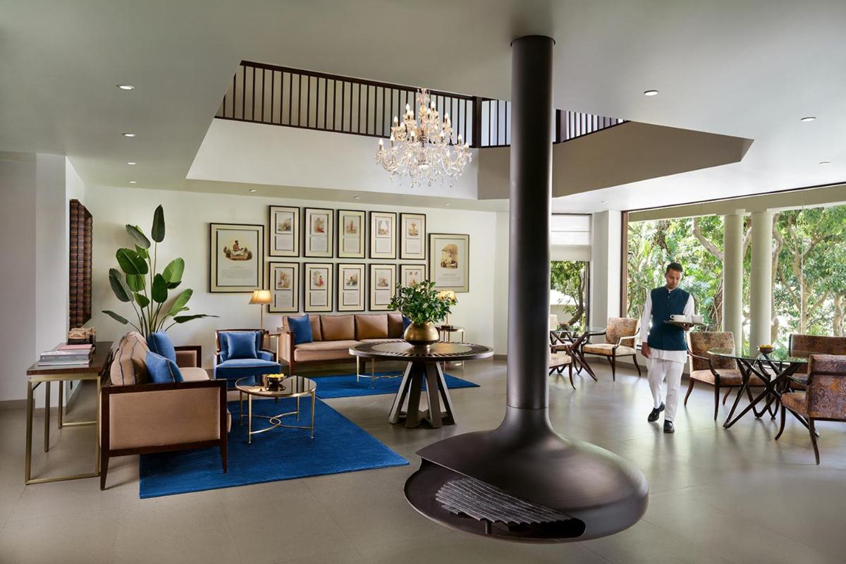 a person walking through a living room with a fireplace at Anand Kashi by the Ganges Rishikesh - IHCL Seleqtions in Rishīkesh