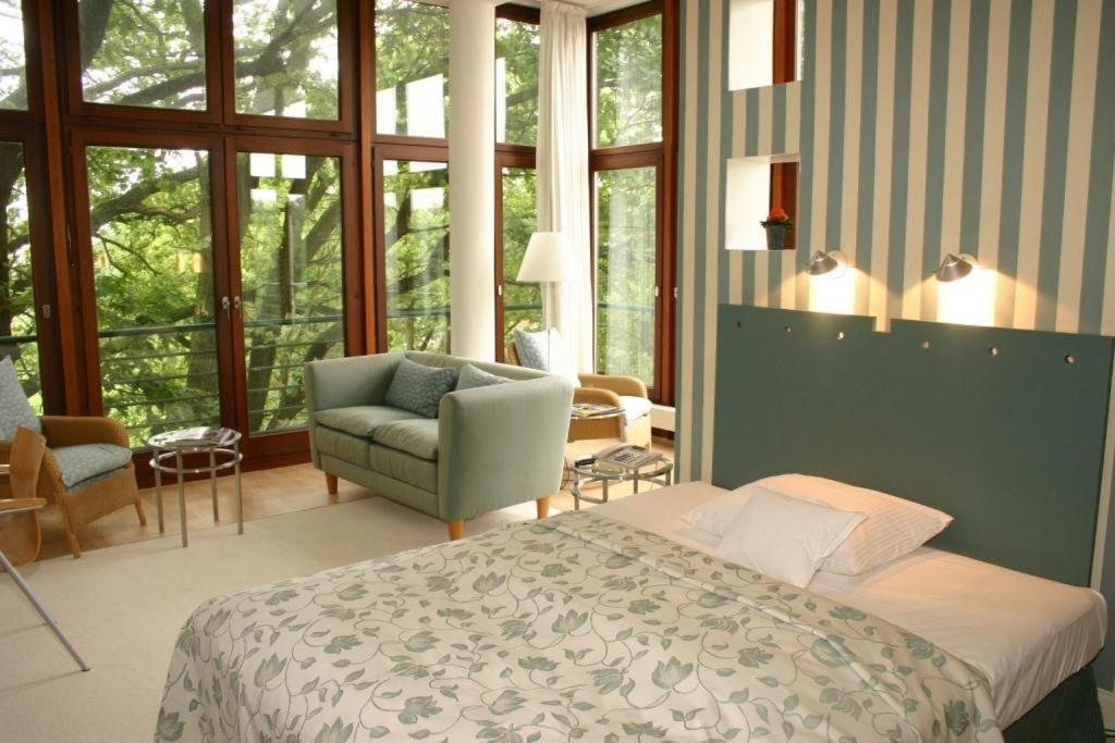 ein Schlafzimmer mit einem Bett und einem Stuhl und Fenstern in der Unterkunft Privathotel Lindtner Hamburg in Hamburg + 37 Fotos ein Schlafzimmer mit einem Bett und einem Stuhl und Fenstern in der Unterkunft Privathotel Lindtner Hamburg in Hamburg + 37 Fotos