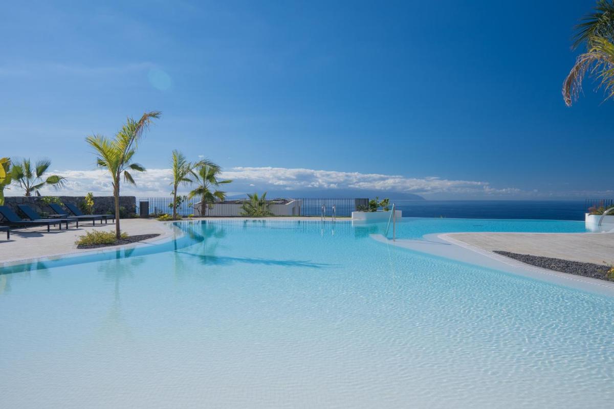Una gran piscina con vista al mar. en Los Jardines de Abama Suites & Villas, en Guía de Isora
