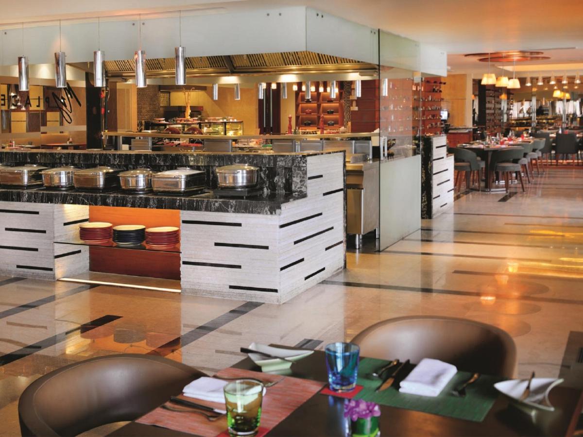 a restaurant with a large kitchen with tables and chairs at Gokulam Grand Hotel & Spa Bangalore in Bengaluru a restaurant with a large kitchen with tables and chairs at Gokulam Grand Hotel & Spa Bangalore in Bengaluru
