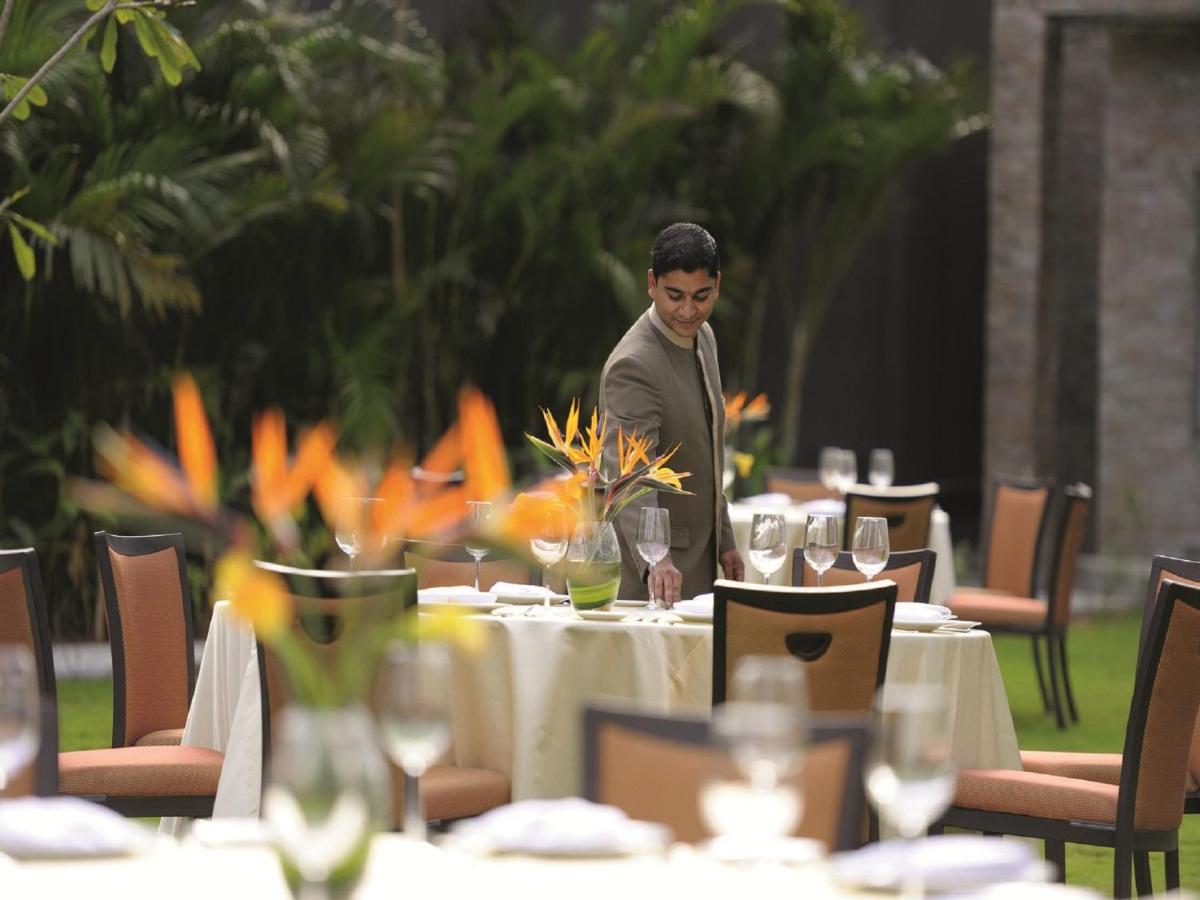 a man standing in front of a table in a restaurant at Gokulam Grand Hotel & Spa Bangalore in Bengaluru a man standing in front of a table in a restaurant at Gokulam Grand Hotel & Spa Bangalore in Bengaluru