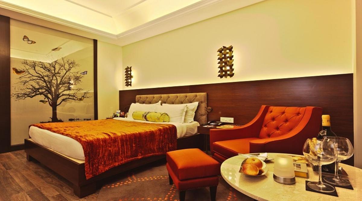 a hotel room with a bed and a chair at Hotel Hindusthan International, Kolkata in Kolkata