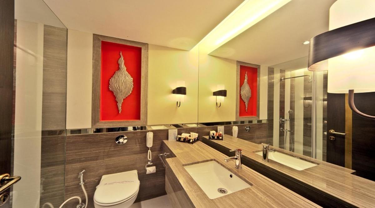a bathroom with a sink and a red painting on the wall at Hotel Hindusthan International, Kolkata in Kolkata a bathroom with a sink and a red painting on the wall at Hotel Hindusthan International, Kolkata in Kolkata