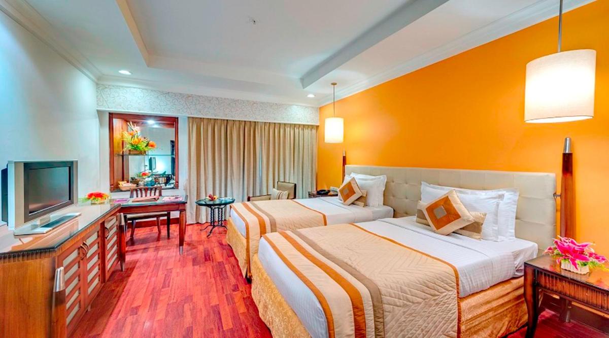 a hotel room with two beds and a television at Hotel Hindusthan International, Kolkata in Kolkata