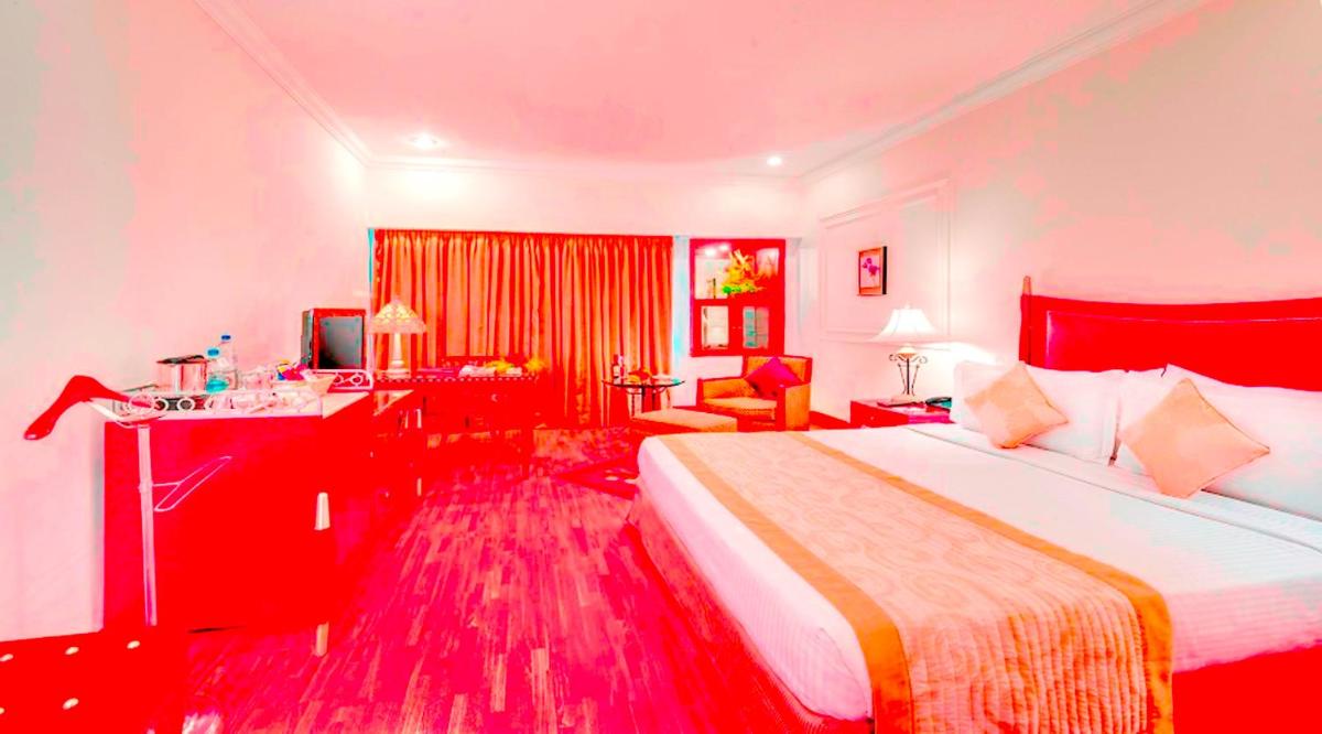 a hotel room with a large bed and a desk at Hotel Hindusthan International, Kolkata in Kolkata