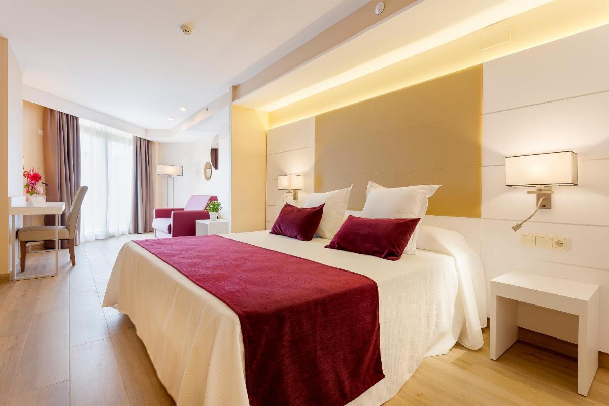 Una habitación de hotel con una cama grande con almohadas rojas. en Hotel Beverly Park & Spa, en Blanes