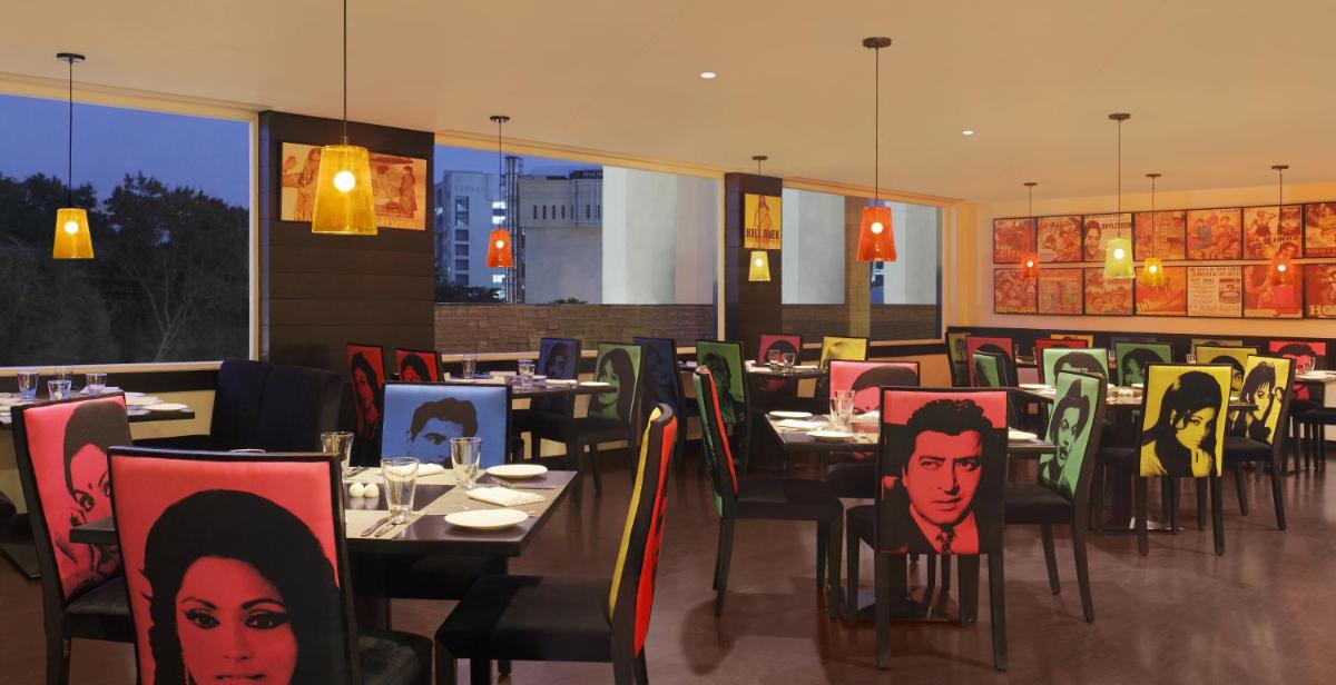 a restaurant with tables and chairs with portraits on them at Lemon Tree Premier Hitec City Hyderabad in Hyderabad