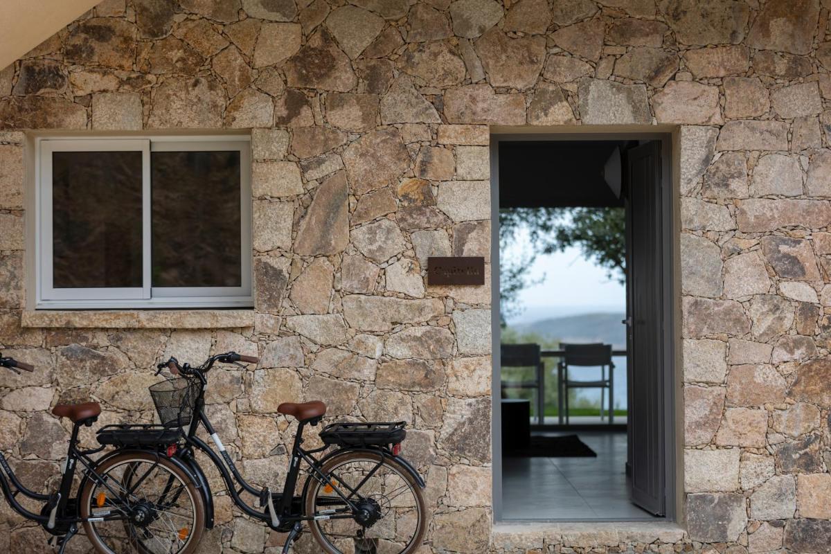 deux vélos garés sur le côté d'un mur de pierre dans l'établissement Résidence Omigna, à Cargèse
