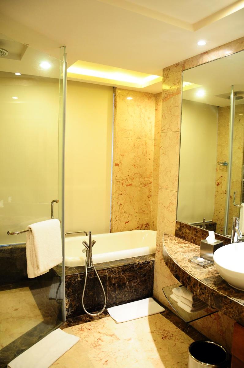a bathroom with a tub and a sink and a shower at Radisson Blu Plaza Delhi Airport in New Delhi a bathroom with a tub and a sink and a shower at Radisson Blu Plaza Delhi Airport in New Delhi