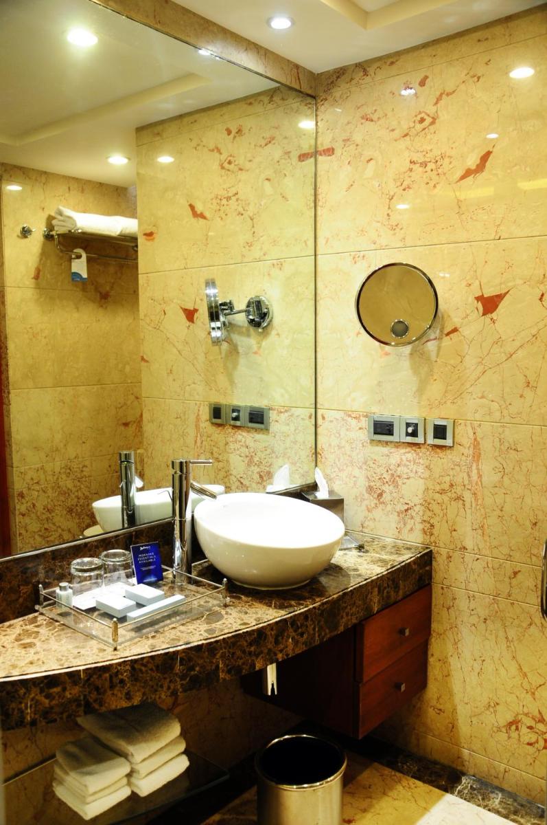 a bathroom with a sink and a mirror at Radisson Blu Plaza Delhi Airport in New Delhi a bathroom with a sink and a mirror at Radisson Blu Plaza Delhi Airport in New Delhi