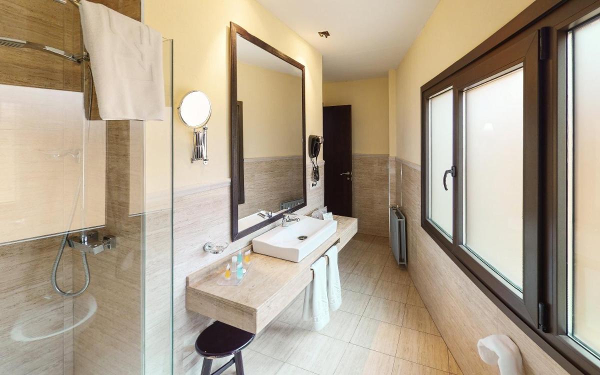 Un baño con lavabo, espejo y ducha. en Hotel Sierra de Cazorla & SPA 3*, en Cazorla