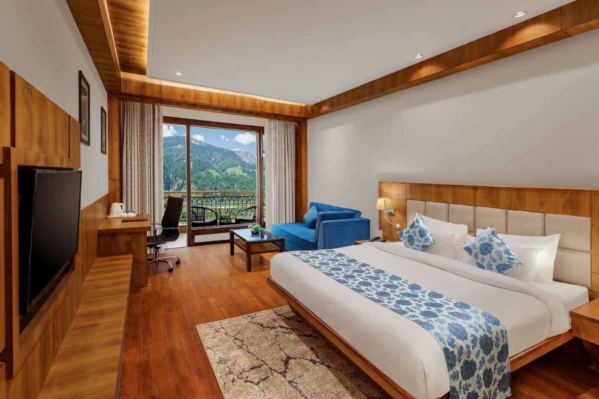 a hotel room with a bed and a television at The Orchid Manali - a Boutique Hotel in Manāli a hotel room with a bed and a television at The Orchid Manali - a Boutique Hotel in Manāli