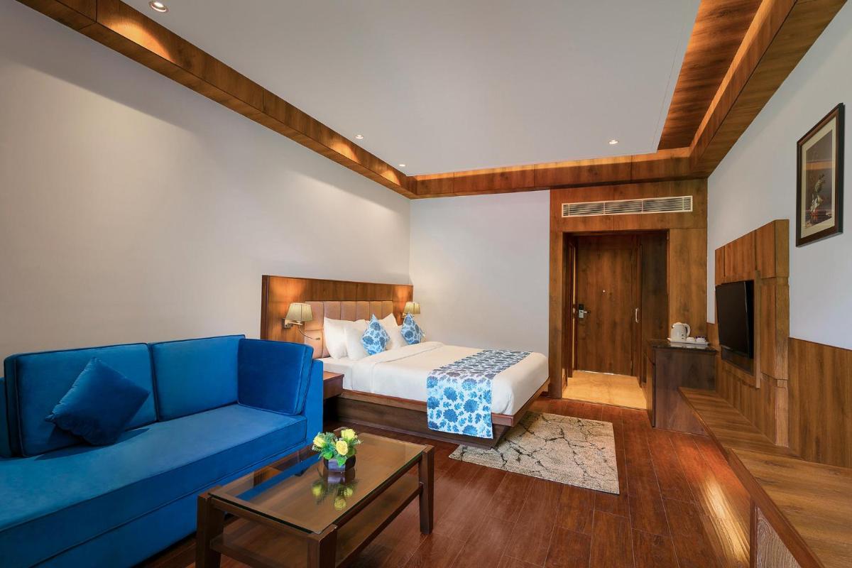 a living room with a blue couch and a bed at The Orchid Manali - a Boutique Hotel in Manāli a living room with a blue couch and a bed at The Orchid Manali - a Boutique Hotel in Manāli