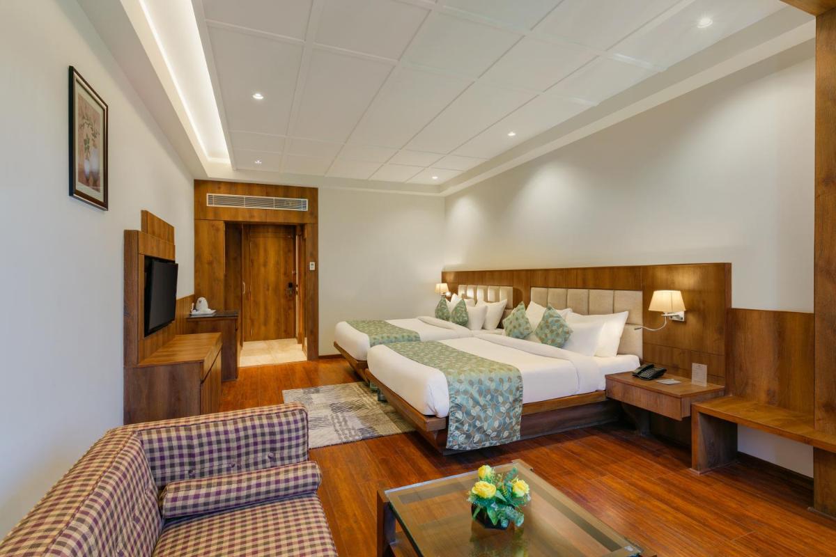 a hotel room with a bed and a couch at The Orchid Manali - a Boutique Hotel in Manāli a hotel room with a bed and a couch at The Orchid Manali - a Boutique Hotel in Manāli