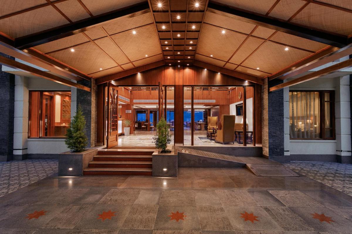 a lobby of a building with stairs and potted plants at The Orchid Manali - a Boutique Hotel in Manāli a lobby of a building with stairs and potted plants at The Orchid Manali - a Boutique Hotel in Manāli