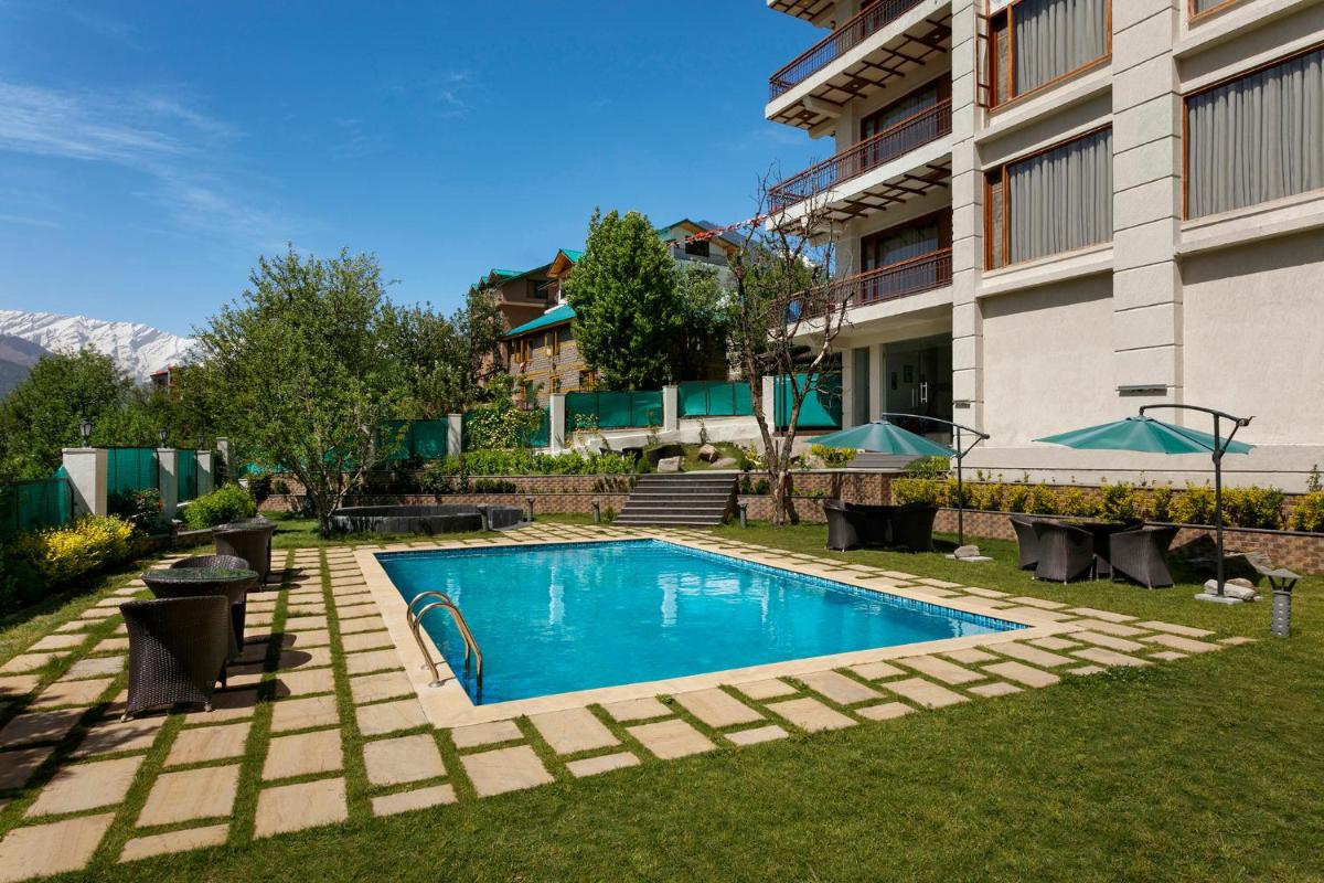 a swimming pool in a yard next to a building at The Orchid Manali - a Boutique Hotel in Manāli a swimming pool in a yard next to a building at The Orchid Manali - a Boutique Hotel in Manāli