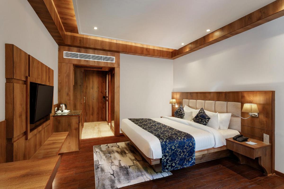 a bedroom with a bed and a flat screen tv at The Orchid Manali - a Boutique Hotel in Manāli a bedroom with a bed and a flat screen tv at The Orchid Manali - a Boutique Hotel in Manāli
