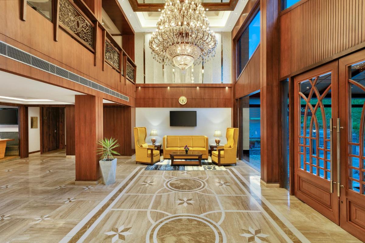 a lobby with yellow chairs and a chandelier at The Orchid Manali - a Boutique Hotel in Manāli a lobby with yellow chairs and a chandelier at The Orchid Manali - a Boutique Hotel in Manāli