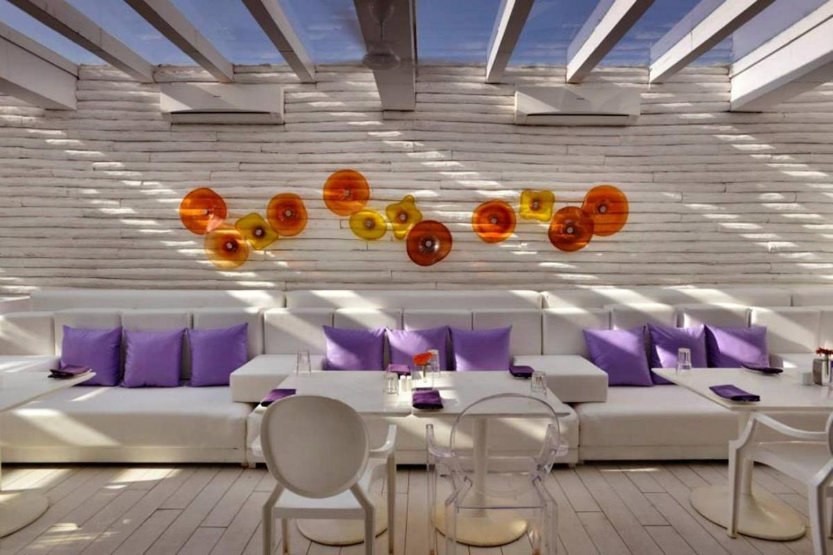 a dining room with white furniture and purple pillows at The Park Calangute Goa in Calangute a dining room with white furniture and purple pillows at The Park Calangute Goa in Calangute
