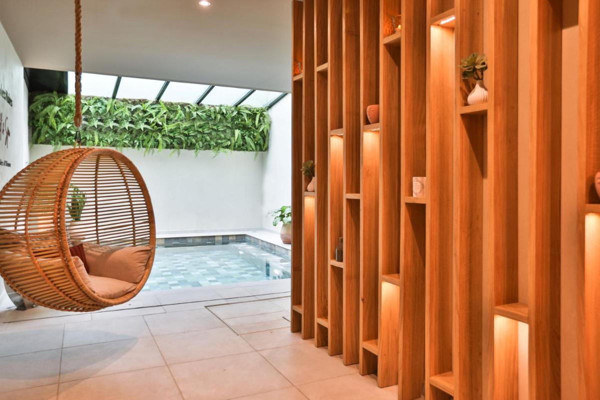 une chambre avec une chaise suspendue et une piscine dans l'établissement Hotel & Spa Les Roches Noires, à Les Sables-dʼOlonne