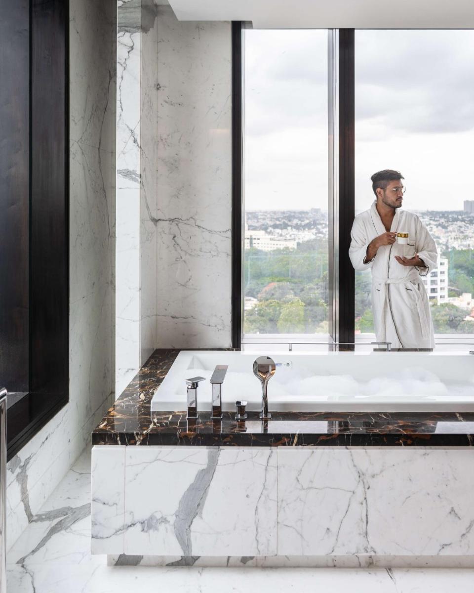 a man standing in a bathroom with a bath tub at Shangri-La Bengaluru in Bengaluru a man standing in a bathroom with a bath tub at Shangri-La Bengaluru in Bengaluru