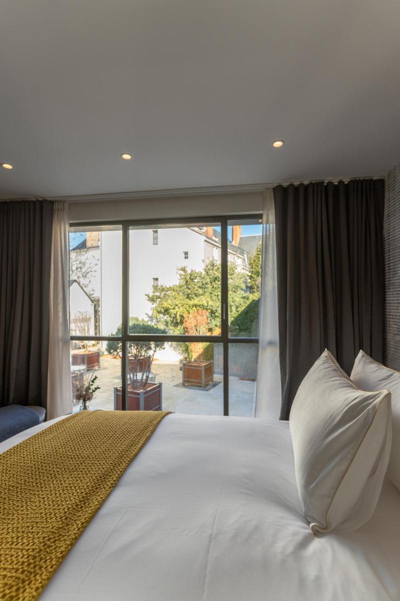 une chambre avec un lit blanc avec une grande fenêtre dans l'établissement Les Trésorières, à Tours