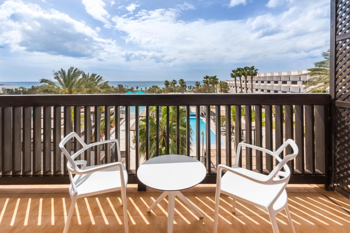 Dos sillas y una mesa en el balcón de un resort. en Barceló Cabo de Gata, en Retamar