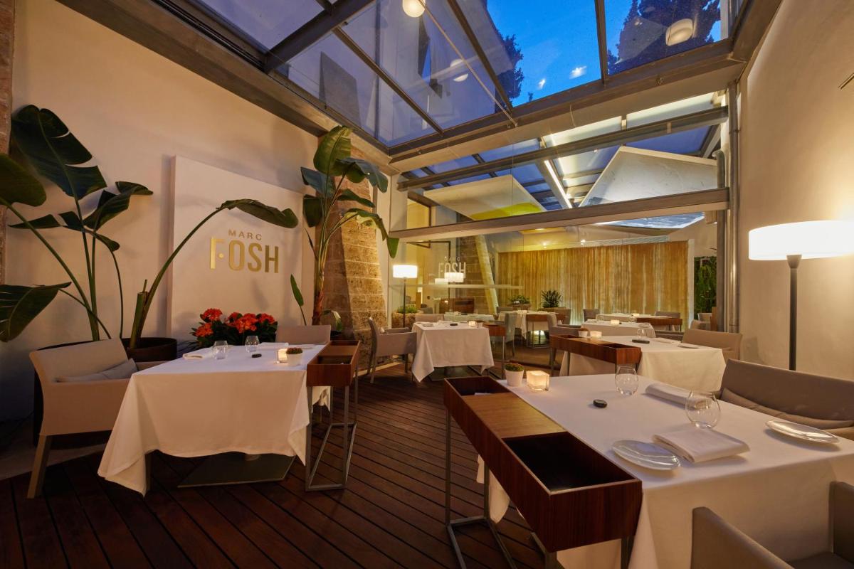 Un restaurante con mesas y sillas blancas y un techo de cristal. en Convent de la Missio - Grand Luxury Boutique hotel, Adults Only, en Palma de Mallorca