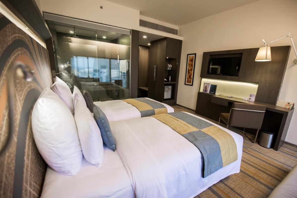 a hotel room with a large bed with pillows at Novotel Kolkata Hotel and Residences in Kolkata a hotel room with a large bed with pillows at Novotel Kolkata Hotel and Residences in Kolkata