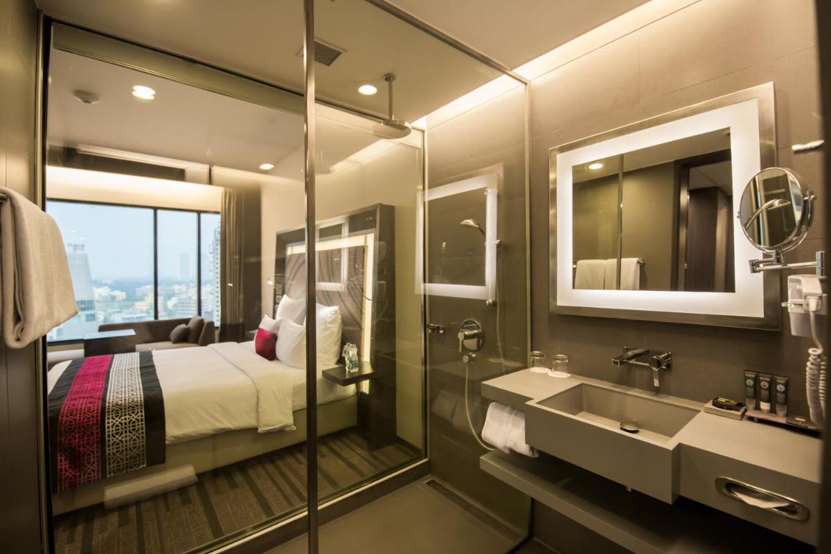 a bathroom with a bed and a sink and a mirror at Novotel Kolkata Hotel and Residences in Kolkata a bathroom with a bed and a sink and a mirror at Novotel Kolkata Hotel and Residences in Kolkata