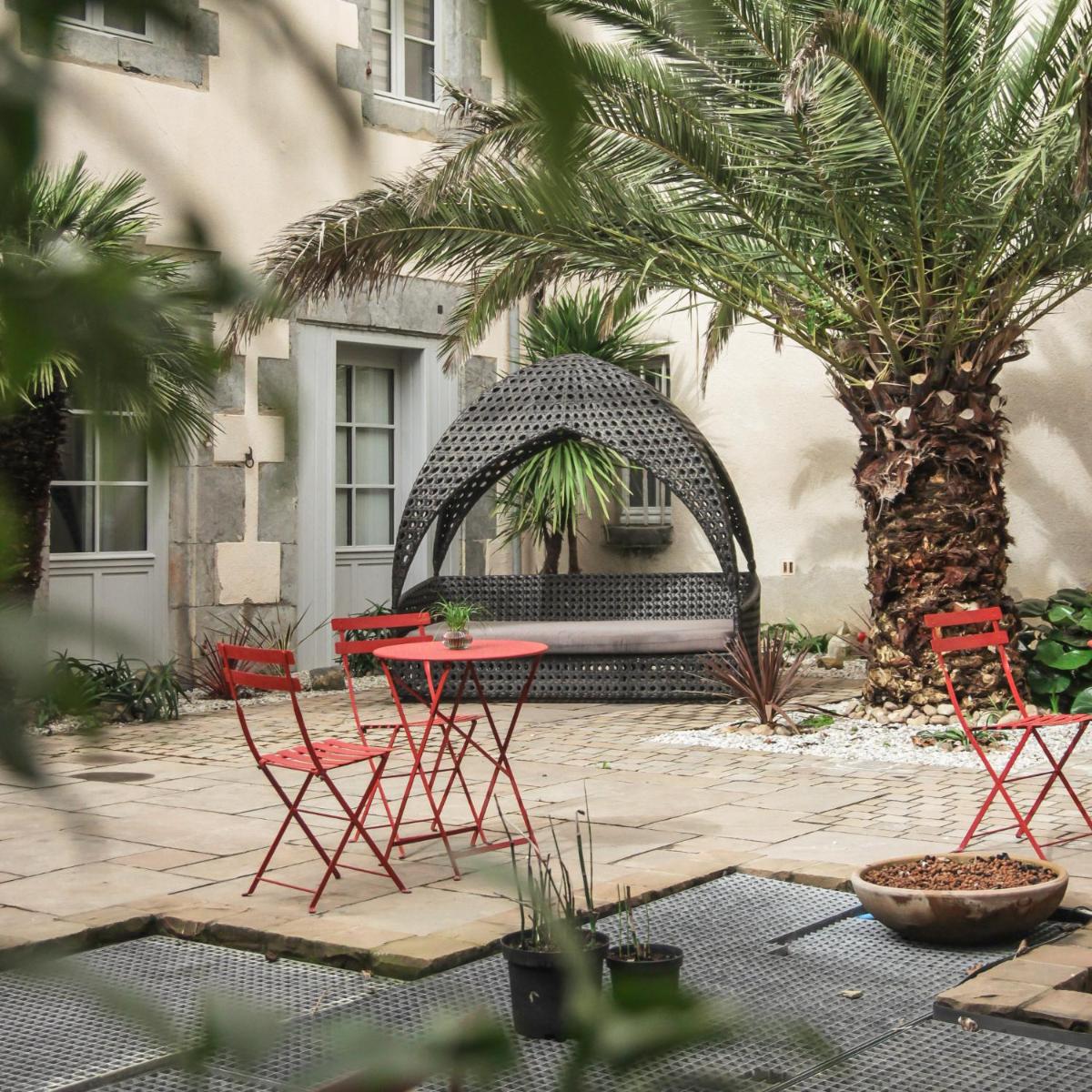 d'un patio avec des chaises rouges et une table dans une cour. dans l'établissement Hôtel Le Petit Périer, à Laval