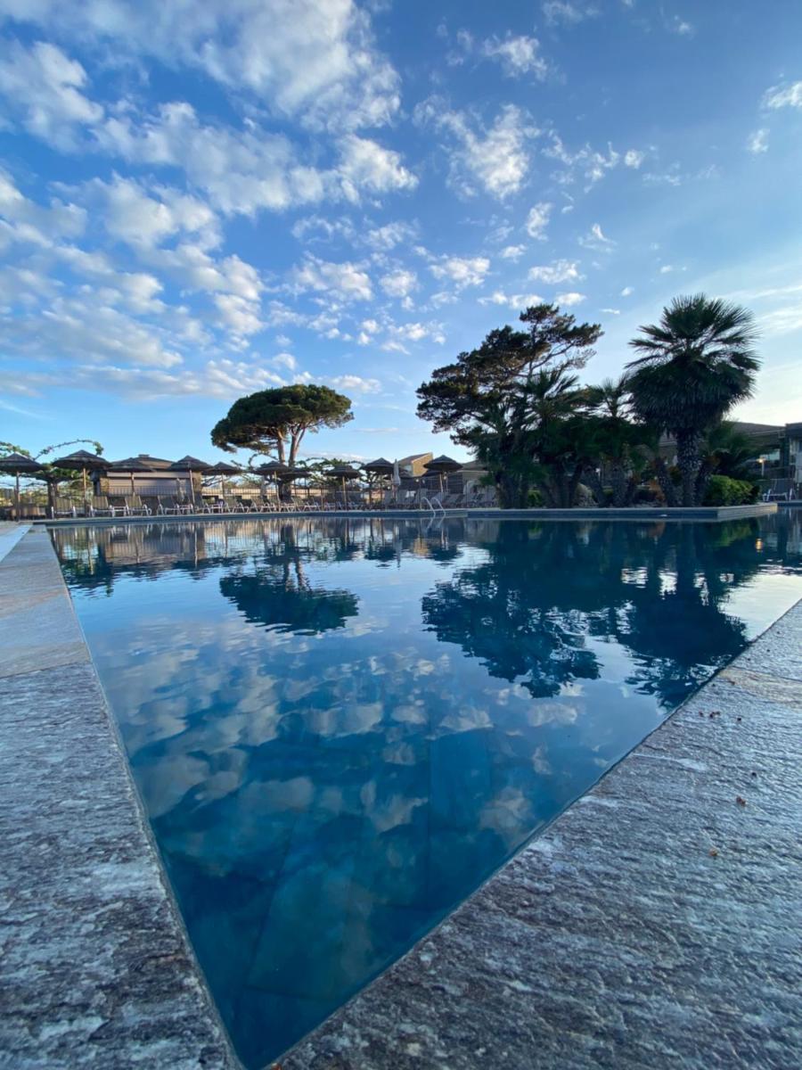 un bassin d'eau avec des arbres en arrière-plan dans l'établissement Hôtel La Lagune, à Lucciana