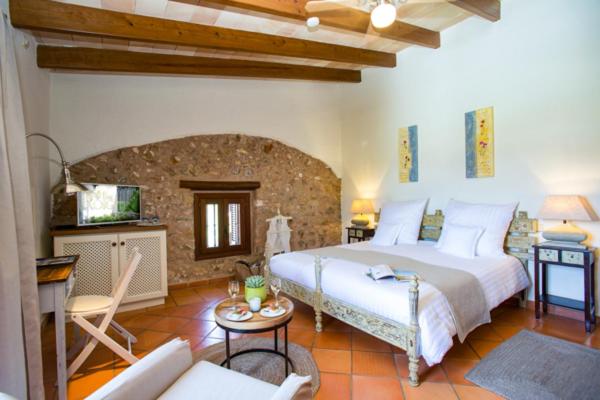 Un dormitorio con una cama grande y una sala de estar. en Casa Font i Roig, en Maria de la Salut