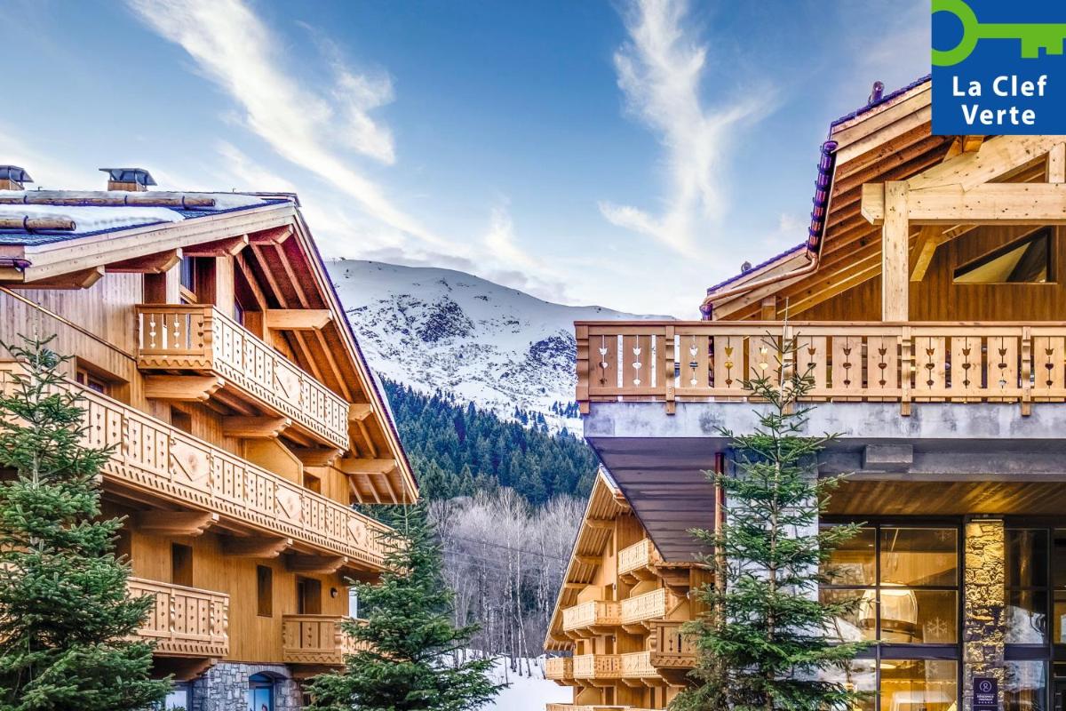 un immeuble de villégiature avec un balcon et des montagnes en arrière-plan dans l'établissement Résidence Pierre & Vacances Premium L'Hévana, à Méribel