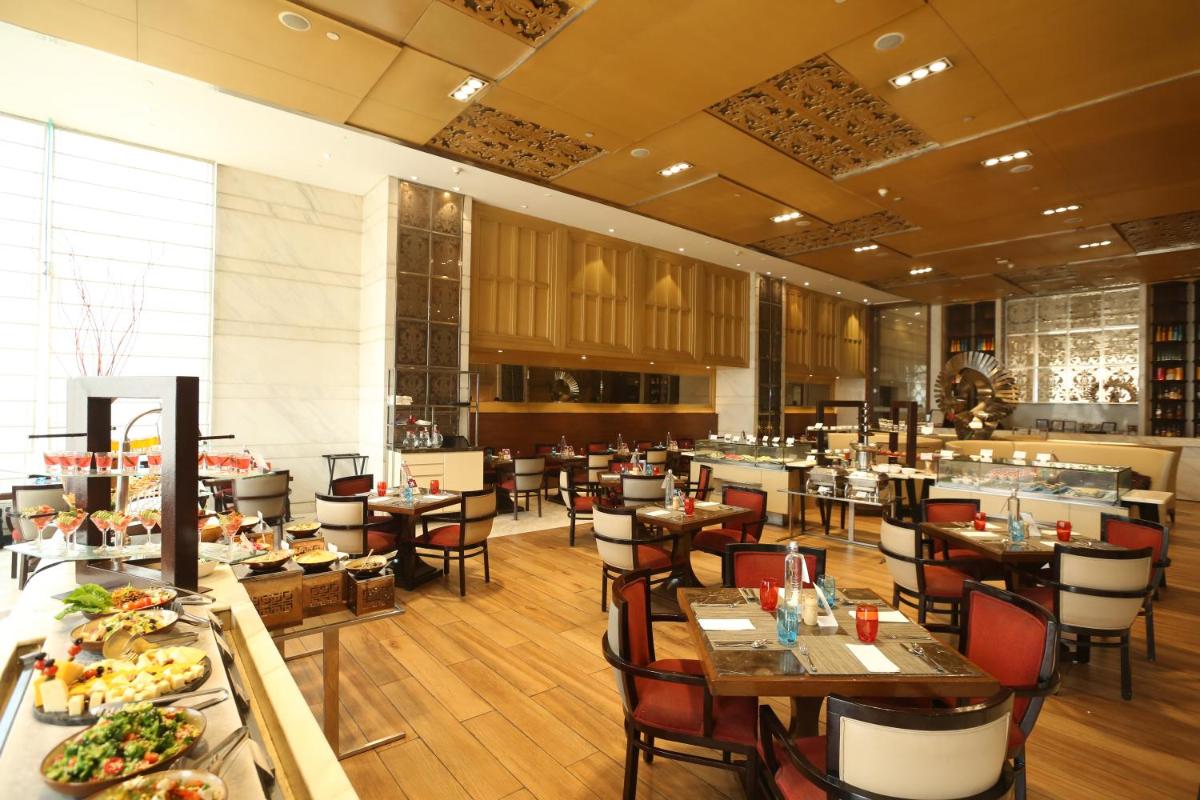 a dining room with tables and chairs in a restaurant at Crowne Plaza New Delhi Mayur Vihar Noida by IHG in New Delhi