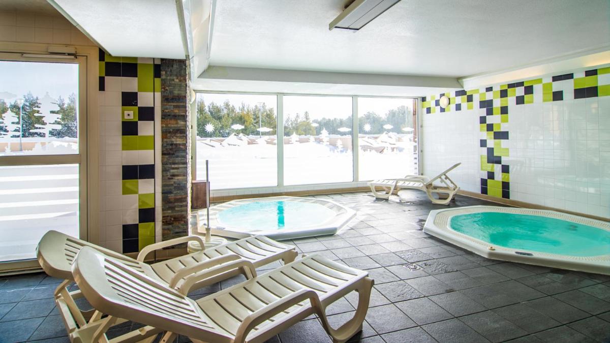 La salle de bains est pourvue d'un bain à remous, de chaises et d'une piscine. dans l'établissement Vacancéole - Appart'Vacances Pyrénées 2000, à Bolquère-Pyrénées 2000