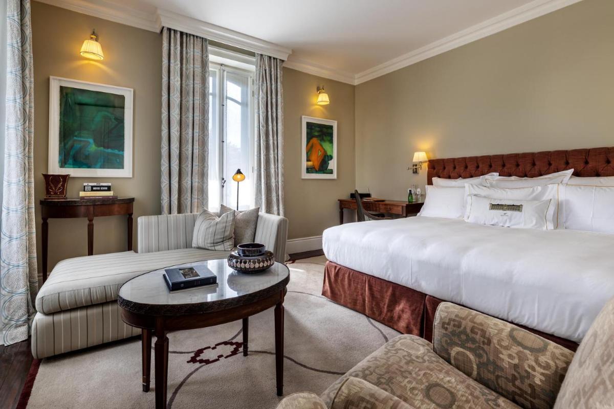 um quarto de hotel com uma cama grande e um sofá em Vidago Palace em Vidago